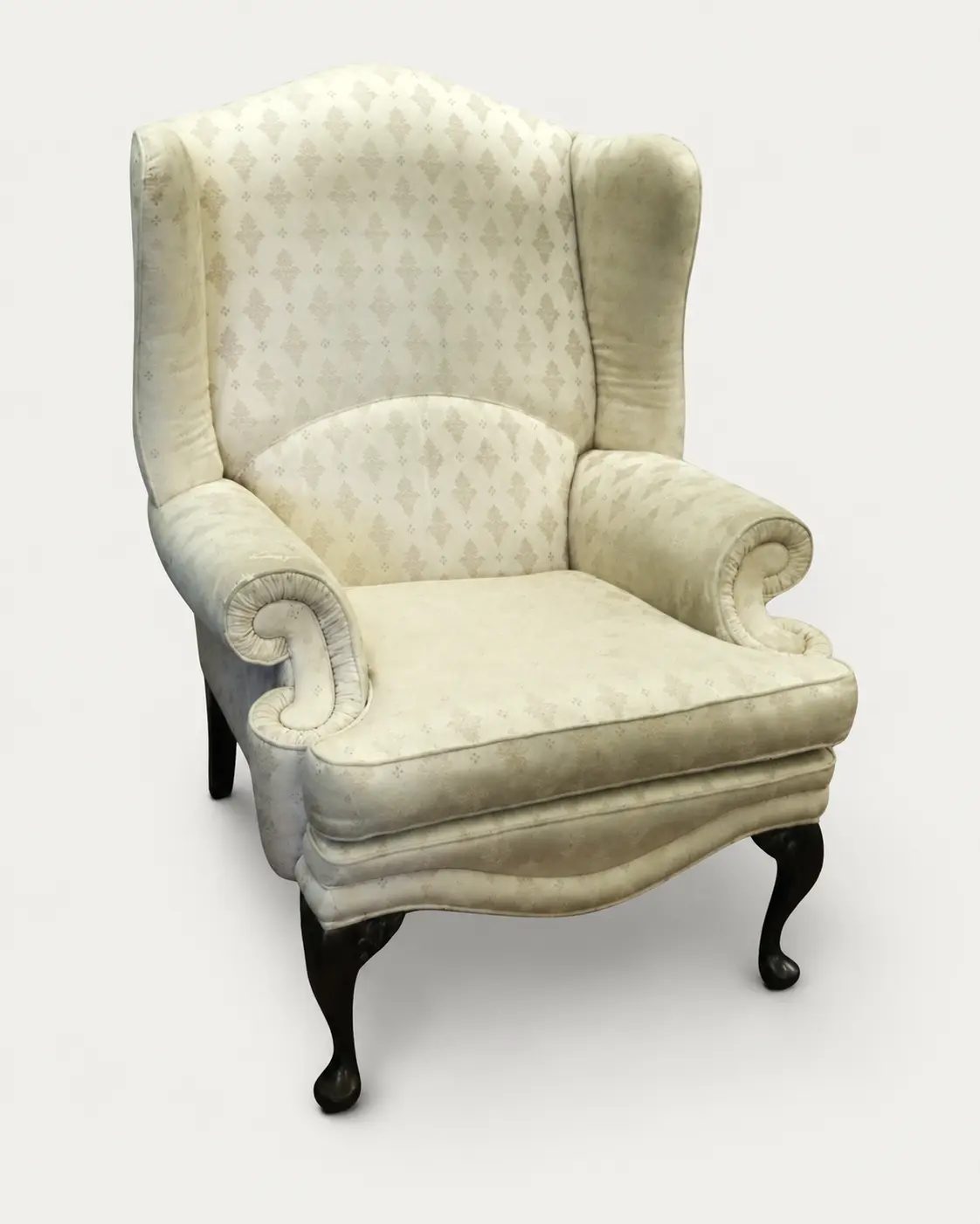The same wingback chair before re-upholstery, in its original faded cream fabric